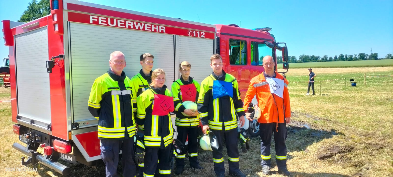 Wettbewerbsgruppe aufgestellt vor dem Fahrzeug