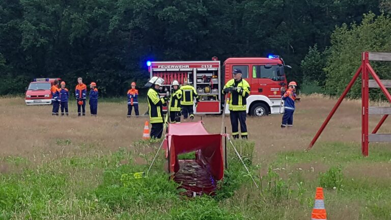 Übung Jugendfeuerwehr auf einer Wiese mit Unterstützung von aktiven Kameraden