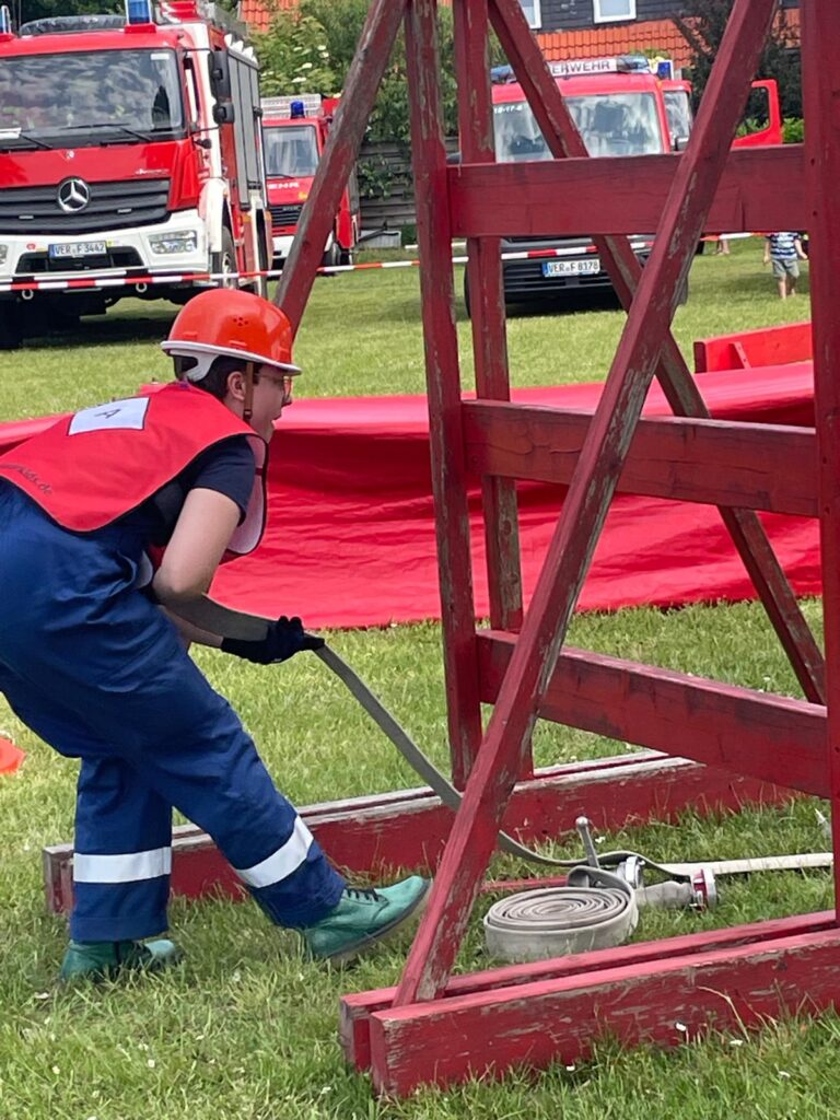Hannah sieht den gerollten Schlauch unter der Leiterwand gerade