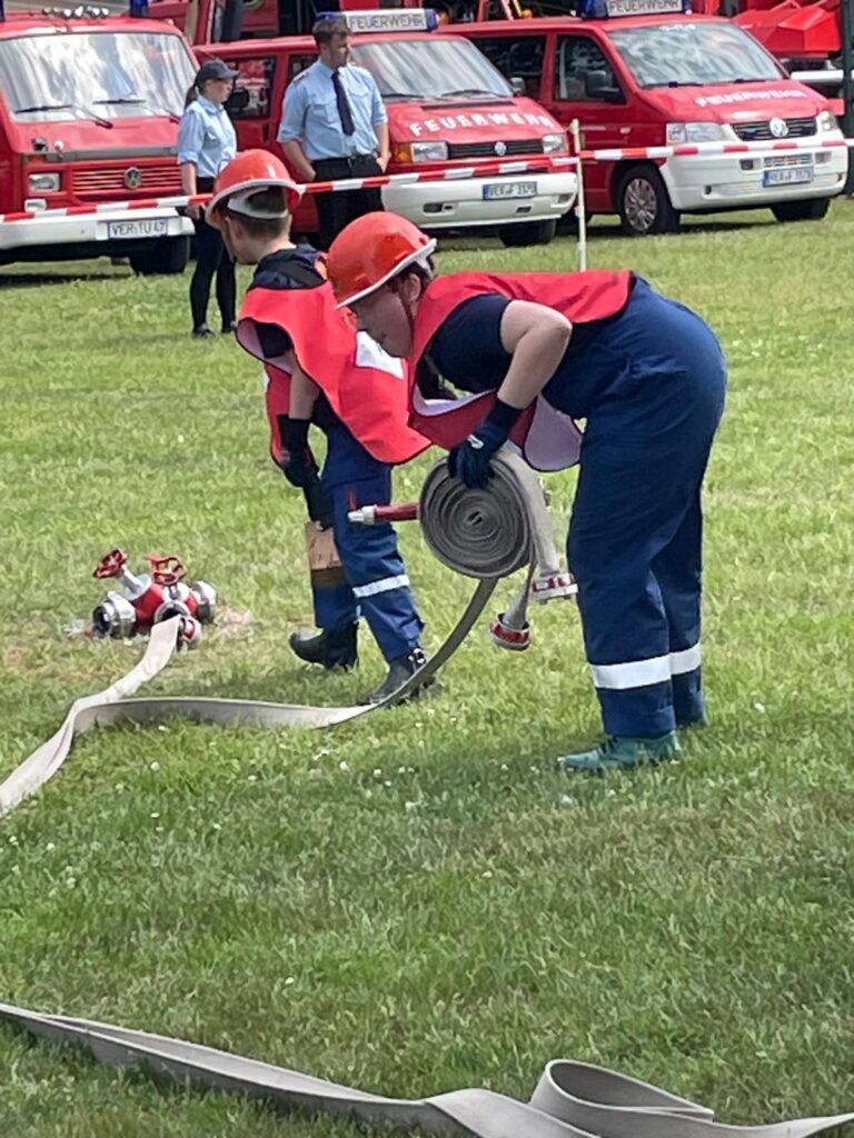Hannah rüstet sich am Verteiler mit C-Schlauch und Strahlrohr aus