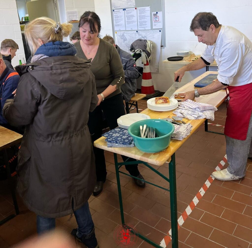 Pizza essen im Feuerwehrhaus. Mario verteielt die Pizzen auf die Teller